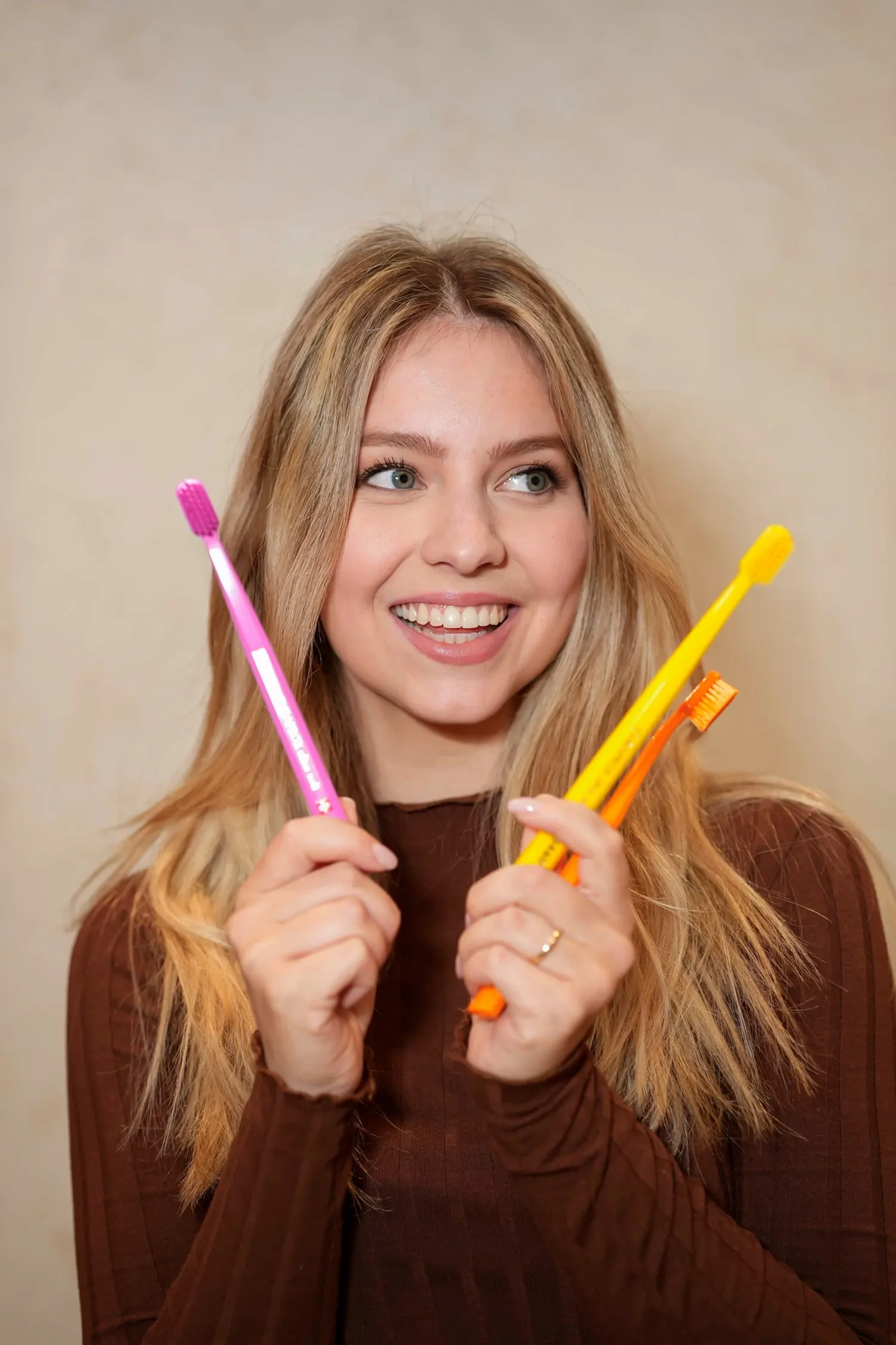 A young woman holding two toothbrushes