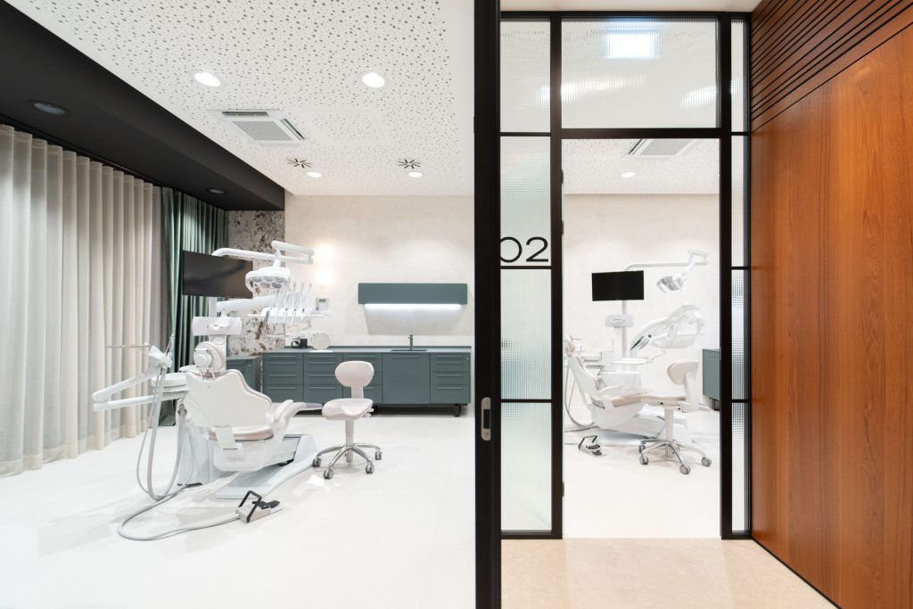 A DC360 treatment room with a dental chair behind a glass partition